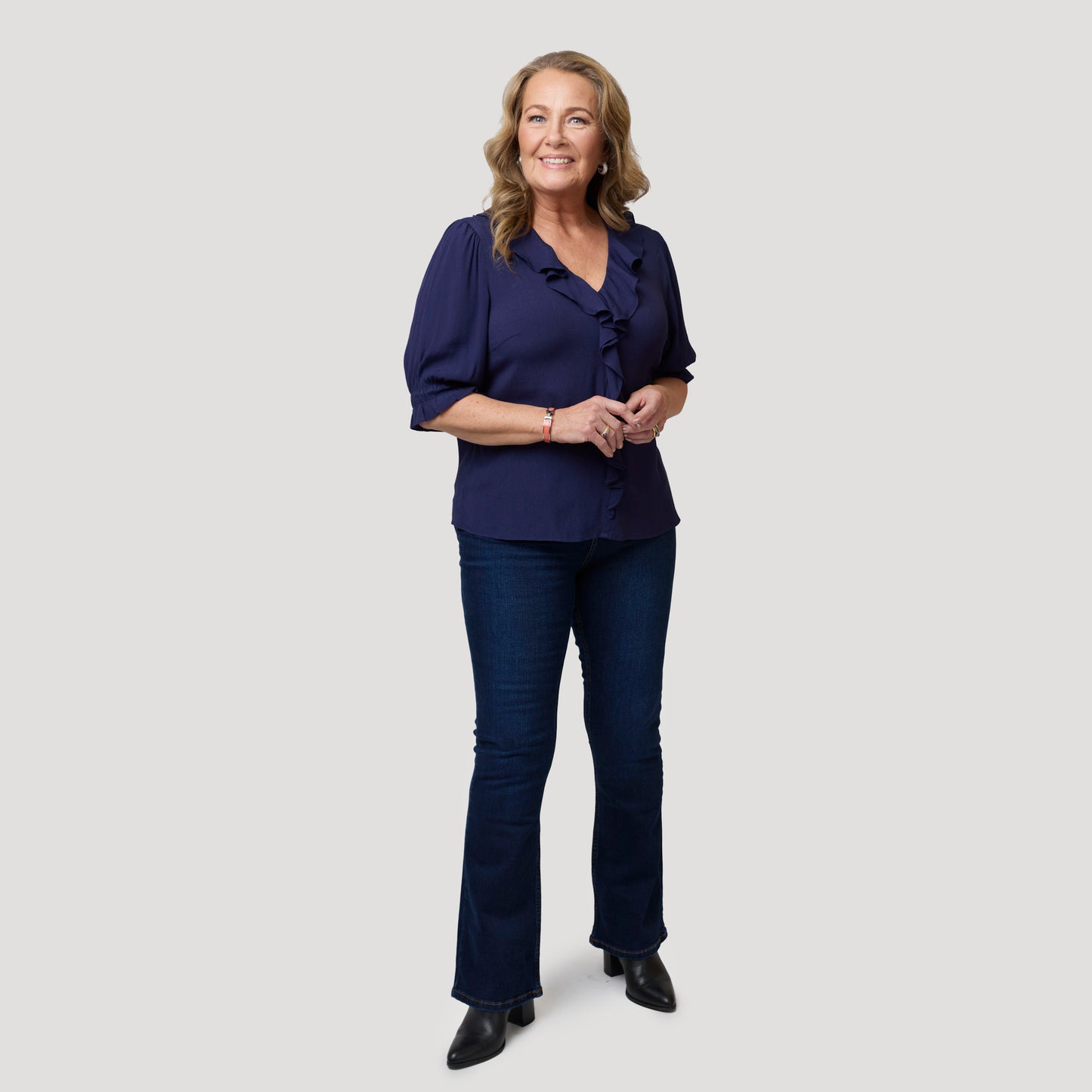 Tummansininen pusero volangilla tummien farkkujen kanssa