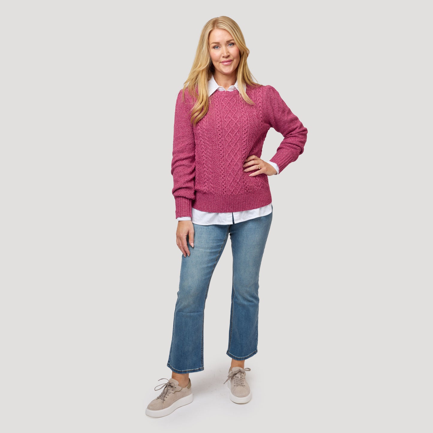 Valkoinen kauluspaita vadelmanpinkin palmikkoneuleen alla